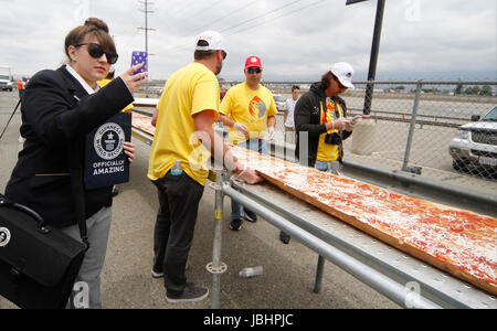 June 10, 2017. Fontana CA. Guinness Book of World Records official Christina Conton watches over the making of the worlds longest 1.3 mile long pizza at the Auto Club Speedway in Fontana California Saturday. The cooking of the pizza started at 11am and finish at 4pm outside the race track. The making of the pizza started Friday at 7pm with the pizza dough being made, cook and laid out along a 1.3 mile lone table. The making of the pizza consist of 530 gallons of tomato sauce, 20,000 pounds of dough, 15,000 pounds of cheese, 1.3 mile long table, 3 mobile pizza ovens, hundreds of pizza boxes a Stock Photo
