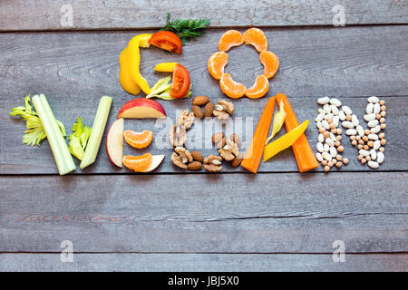 Words "Go Vegan" written with vegetables, fruits, nuts and legumes on rustic wooden background, concept - organic ingredients for healthy vegan food a Stock Photo