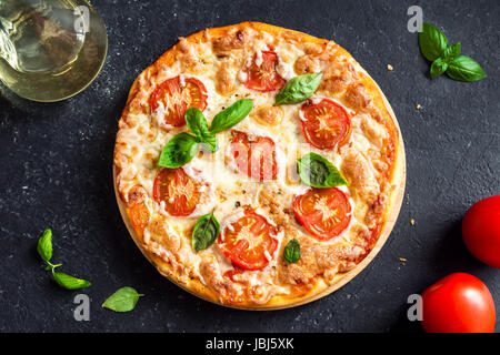 Pizza Margherita on black stone background. Homemade Pizza Margarita with Tomatoes, Basil and Mozzarella Cheese. Stock Photo