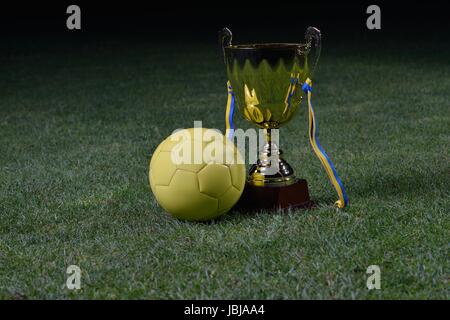Golden soccer cup and ball on grass field Stock Photo
