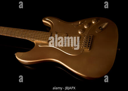 Close up of a gold electric guitar on a dark background at an oblique angle with detail of the strings Stock Photo