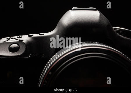 Professional modern DSLR camera low key image - Modern DSLR camera with a very wide aperture lens on Stock Photo