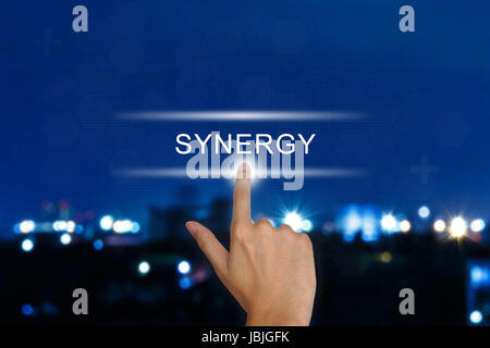 hand clicking synergy button on a touch screen interface Stock Photo