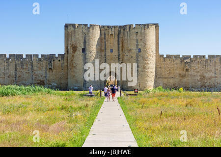 Tourists entering the old town through one of the main medieval gateways of Aigues Mortes, Nimes, Gard, Occitanie, France Stock Photo