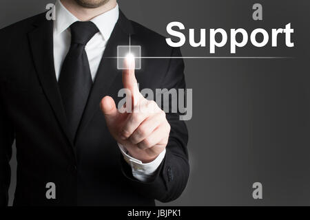 man in black suite pressing virutal button support Stock Photo