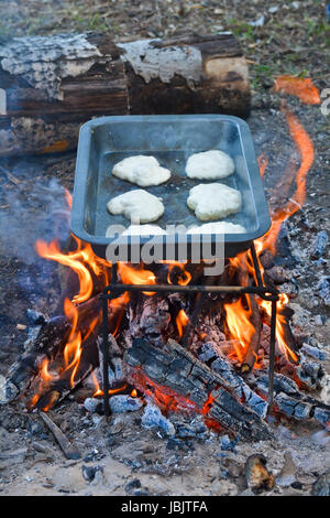 Breakfast at the stake. Preparation of pancakes on a baking sheet over a fire flame. Stock Photo