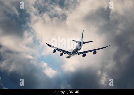 Flight in bad weather. Airplane flying under dramatic storm clouds. Stock Photo