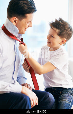 Photo of happy boy tying necktie of his father Stock Photo
