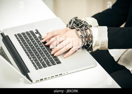 Closeup photo of female hand chained up to laptop Stock Photo