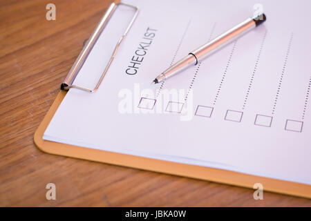 Checklist concept - checklist, paper and a pen with checklist word on wooden table Stock Photo