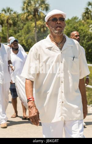 Public radio host of the Roots Musik Karamu show, Osei Chandler, leads descendants of enslaved Africans brought to Charleston in the Middle Passage in a procession during a remembrance ceremony at Fort Moutrie National Monument June 10, 2017 in Sullivan's Island, South Carolina. The Middle Passage refers to the triangular trade in which millions of Africans were shipped to the New World as part of the Atlantic slave trade. An estimated 15% of the Africans died at sea and considerably more in the process of capturing and transporting. Stock Photo