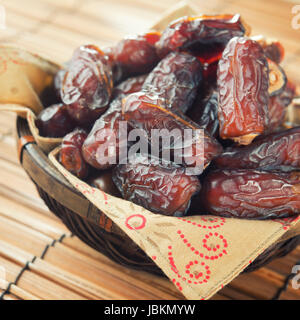 Pile of fresh dried date fruits in bamboo basket. Dried date palm fruits or kurma, ramadan food which eaten in fasting month. Stock Photo