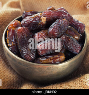 Pile of fresh dried date fruits in metal bowl. Dried date palm fruits or kurma, ramadan food which eaten in fasting month. Stock Photo