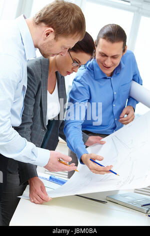 Three engineers examining a sketch of plane Stock Photo
