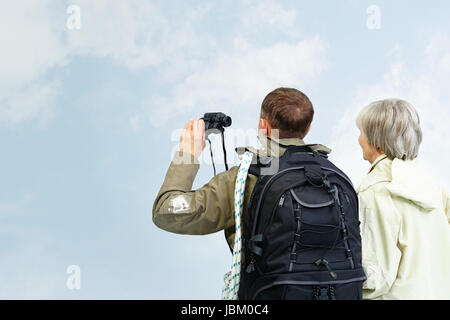Backs of senior hikers with binoculars on trip Stock Photo