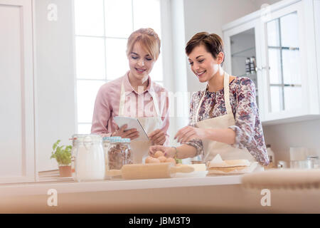 Female caterers with digital tablet baking in kitchen Stock Photo