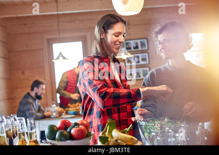 Friends tossing salad in cabin Stock Photo