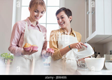 Smiling female caterers baking muffins in kitchen Stock Photo