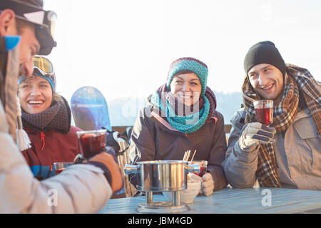 Snowboarder friends drinking cocktails on sunny patio apres-ski Stock Photo