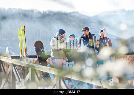 Skier friends talking and drinking cocktails on sunny balcony apres-ski Stock Photo