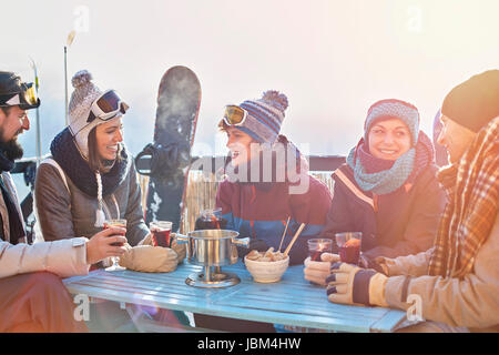 Snowboarder friends drinking cocktails on sunny balcony apres-ski Stock Photo