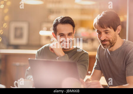Men friends using laptop and drinking coffee in cafe Stock Photo