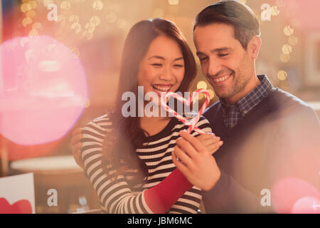 Couple holding heart-shape candy canes Stock Photo