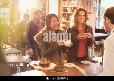 Women talking to barista at cafe counter Stock Photo