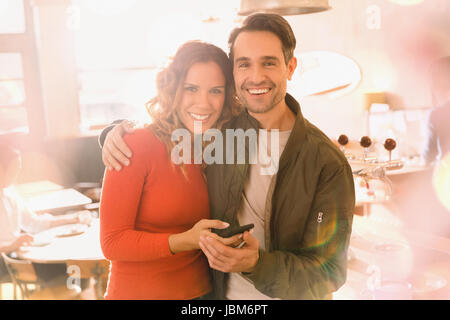 Portrait affectionate smiling couple using cell phone in bar Stock Photo