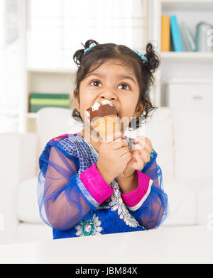 Eating ice cream. Indian Asian girl enjoying an ice cream. Beautiful child model at home. Stock Photo