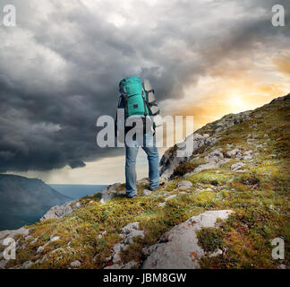 Backpacker in mountains under the thunder clouds