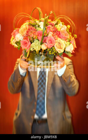 Man carrying vase with flowers. Face obscured.