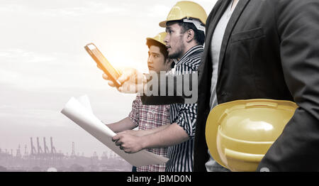 Smart construction in industry 4.0 concept. Double exposure of Business hand suit using mobile phone and two engineers with flare light effect. Stock Photo