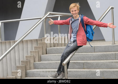 Playful teenage student sliding down railing on school stairway Stock Photo