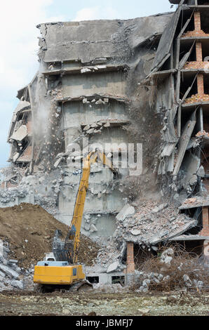 Remove dangerous building in an urban area with an excavator Stock Photo