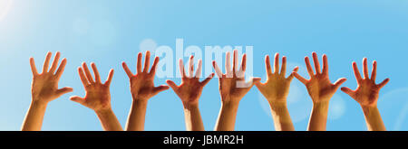 Raised hands on a blue sky background with copy space Stock Photo