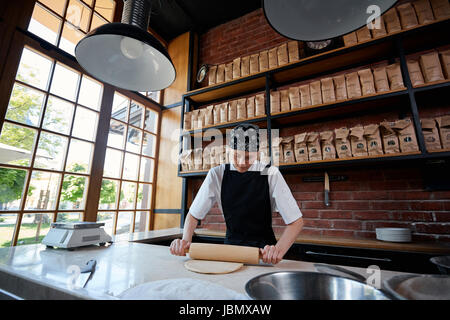 Cheerful woman working with rolling pin Stock Photo