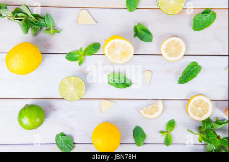Colorful pattern of mint, lime, lemon,ginger slices. . Limes and Lemons sliced and whole with leaves. On white wooden background. Top view. Stock Photo