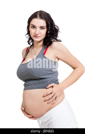 Junge frau mit Babybauch in erwartungsvoller Haltung als Nahaufnahme isoliert vor weißem Hintergrund Stock Photo