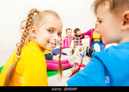 Close-up portrait of blond six years old girl sitting in a circle with friends at school gym Stock Photo