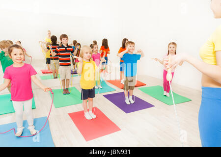Sports coach teaching kids jumping with skipping rope in gym Stock Photo