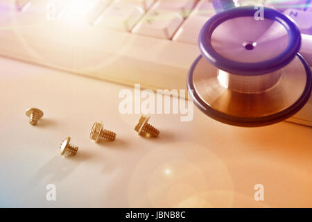 Concept of repairing computers and devices with keyboard, screws and stethoscope background. Elevated view Stock Photo
