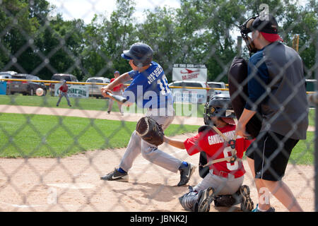 Boy age 12 batting in a baseball game with catcher and umpire. St Paul Minnesota MN USA Stock Photo