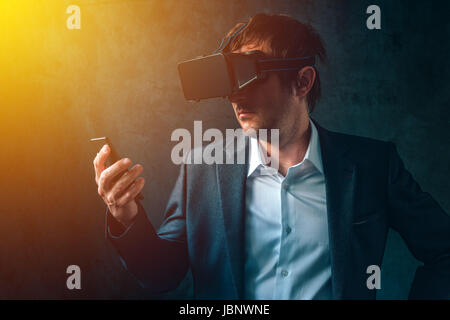 Virtual reality and futuristic technology in modern business, businessman with VR headset and smartphone using new tech gadgets to develop and manage Stock Photo