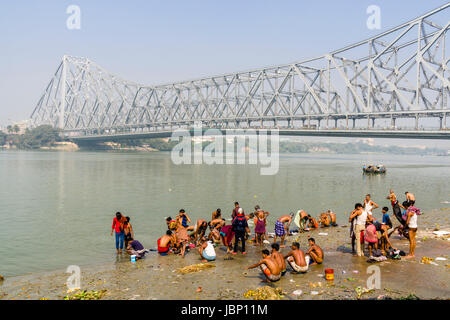 People are having a bath in the Hoogli River under the steel construction of Howrah Bridge Stock Photo