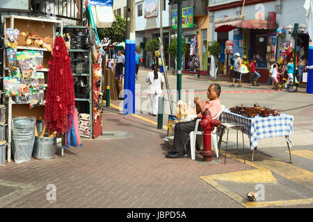 LIMA, PERU - FEBRUARY 13, 2012: Unidentified man selling kitchen utensils and wooden toys at the entrance of the market called Mercado No 1 de Surquillo on February 13, 2012 in Lima, Peru. Stock Photo