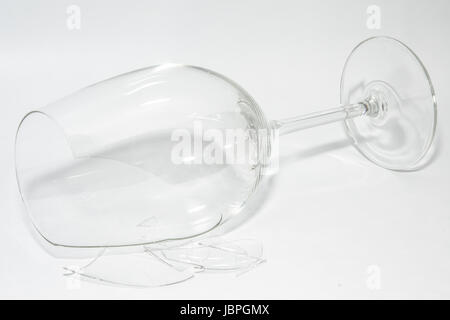 Shattered broken-down wine glass with sharp shards lying on white background Stock Photo