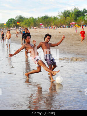 KUTA, BALI ISLAND, INDONESIA - APRIL 4, 2012: People plaing soccer on the beach in Kuta, Indonesia. Football is the most popular sport in Indonesia. The Indonesian football league started around 1930 Stock Photo
