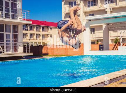 Man doing Somersaul or flip diving into swimming pool Stock Photo
