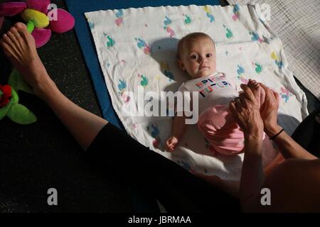 June 12, 2017 - Florida, U.S. - Eight-month-old Emily Rasquin of West Palm Beach participates in an Itsy Bitsy Yoga class at the Mandel Public Library of West Palm Beach Monday, June 12, 2017. ''The interation is great, and it is good for motor development, '' said her mother Amy. According to teacher Kayla Willson of Jupiter, the classes help babies sleep better, digest better, and grow stronger. ''It encourages neuromuscular development and benefits bonding, digestion, sleep, and calm, '' she said. ''They sleep really well after class, which is great for the parents.'' Over the summer, the l Stock Photo